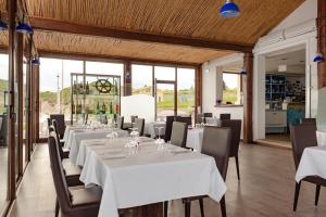 a dining room with white tables and chairs at La Locanda del Mare in Codaruina
