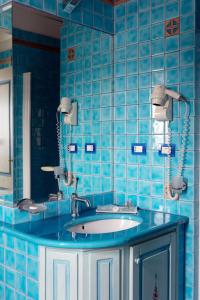 a blue tiled bathroom with a sink and a mirror at La Locanda del Mare in Codaruina +41 photos