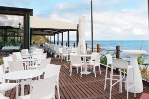 a restaurant with white tables and chairs and the ocean at La Locanda del Mare in Codaruina