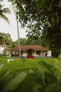 a white house with a red door in a yard at Alleppey Backwater Resort in Alleppey