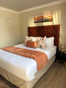 a bedroom with a bed with white sheets and an orange blanket at Iyana Lodge in Grasmere