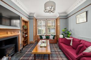 a living room with a red couch and a fireplace at Heywood Cottage in St. Andrews