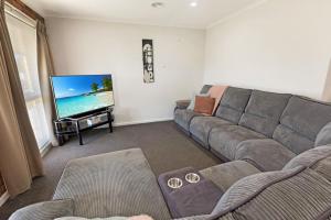 a living room with a couch and a flat screen tv at Maffra Retreat in Maffra