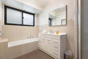 a bathroom with a tub and a sink and a mirror at Maffra Retreat in Maffra +15 photos