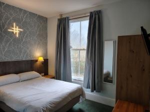 a bedroom with a bed and a window with a cross on the wall at River Hotel in Oxford