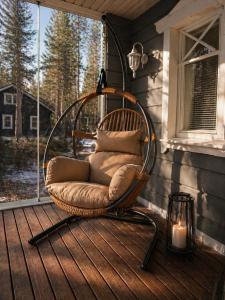 a wicker chair sitting on a porch with a candle at Holiday Cabin Naalinpesä incl Wifi, outdoor jacuzzi for extra fee in Äkäslompolo