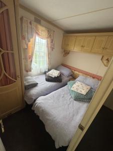a small bedroom with two beds and a window at Home from home in Ingoldmells