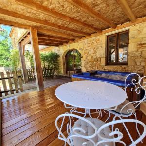 a patio with a table and chairs on a wooden floor at Domaine du Cardou in Puy-lʼÉvêque