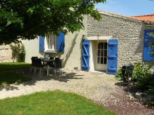 ein Haus mit blauen Türen sowie einem Tisch und Stühlen in der Unterkunft Gîte du Clos de la Vigne in Montreuil
