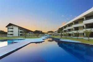 a swimming pool in front of a building at Flat Carneiros Beach Resort in Tamandaré
