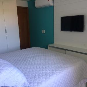 a bedroom with a white bed and a flat screen tv at Flat Carneiros Beach Resort in Tamandaré +10 photos
