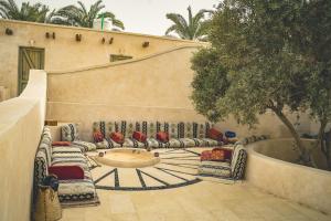 a courtyard with couches and a table and a tree at Asfay Lodge Siwa in Siwa