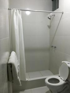 y baño blanco con ducha y aseo. en Hotel El Dorado Inn, en Camaná