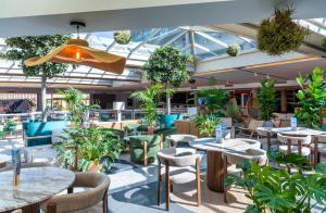 a restaurant with tables and chairs and plants at AQUA Hotel Onabrava & Spa 4*Sup in Santa Susanna