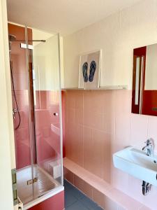 a pink bathroom with a sink and a shower at Familienbett und Sauna - Muschelbude in Wittenbeck