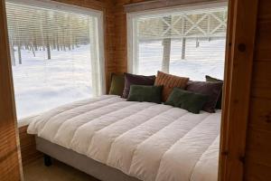 a large bed in a room with a window at Holiday Cabin Naalinpesä incl Wifi, outdoor jacuzzi for extra fee in Äkäslompolo +15 photos