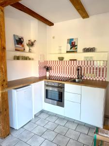 a kitchen with white cabinets and a sink at Familienbett und Sauna - Muschelbude in Wittenbeck +8 photos