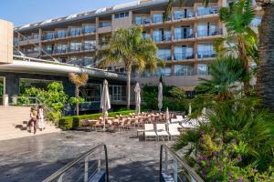 a hotel with tables and chairs in front of a building at AQUA Hotel Onabrava & Spa 4*Sup in Santa Susanna
