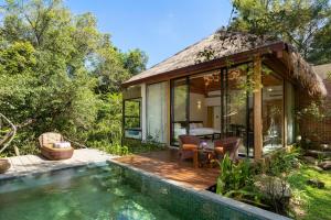 a house with a thatched roof and a swimming pool at AARAWILD Luxury Villas - Sigiriya in Sigiriya