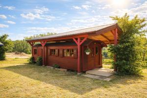 a small red cabin with a roof on a field at Relais Équestre du Neufeld - Roulotte Nature in Oberhaslach