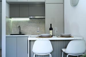 a kitchen with white chairs and a counter with wine glasses at Studio Mare Kotor in Dobrota +10 photos