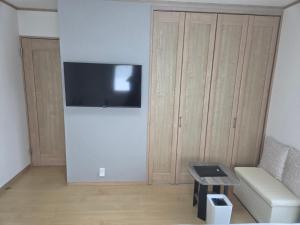 a living room with a couch and a tv on a wall at フルハウス in Fujikawaguchiko