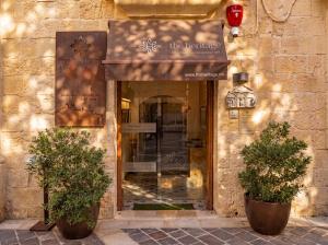 a entrance to a store with two potted trees in front at The Mdina Heritage Boutique Hotel - By Luxury Villas International in Rabat