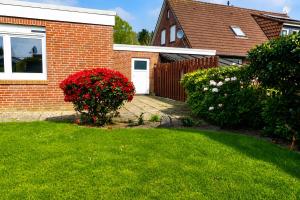a house with a yard with a door and flowers at Ferienhaus Klaus in Berumbur