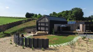 a black house in a field with a fence at Ostara Ecolodge in Saint-Mards-en-Othe