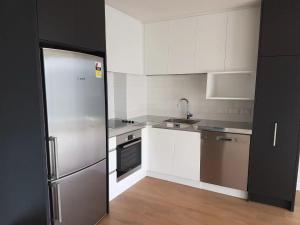 a kitchen with white cabinets and a stainless steel refrigerator at Luxury and Morden Deux & Furry Friends welcome in Auckland