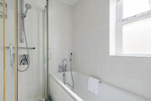 a white bathroom with a shower and a bath tub at Captains Cottage in Deal