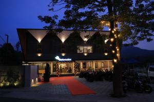 a lit up building with people sitting in front of it at night at Better Suites Hotel in Meppādi