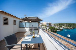 a balcony with a blue table and chairs and the water at Cala Figuera Studio 5b in Cala Figuera
