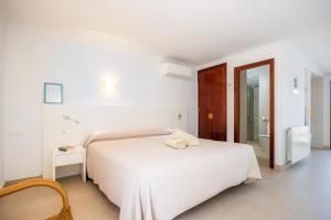 a white bedroom with a white bed and a chair at Cala Figuera Studio 5b in Cala Figuera