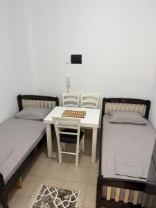 a room with two beds and a table and a desk at Vila 3 palmat in Ksamil