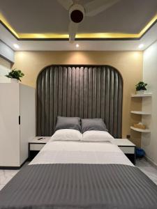 a bedroom with a large bed with a large headboard at Travellers Heaven in Karachi