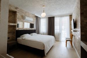 a bedroom with a white bed and a chair at Arya Pansiyon Konyaaltı in Antalya