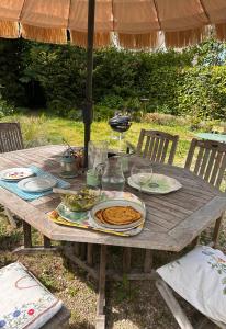 a wooden picnic table with plates of food on it at Le presbytère in Le Crouais +14 photos