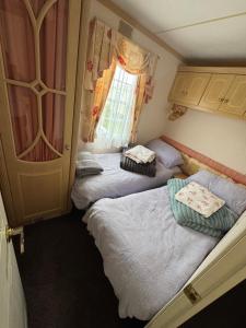 two beds in a small room with a window at Home from home in Ingoldmells