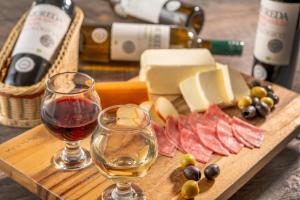 a wooden cutting board with two glasses of wine and cheese at ART HOTEL Nippori Lungwood in Tokyo +36 photos