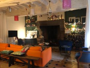 a living room with an orange couch and a fireplace at Le presbytère in Le Crouais