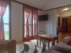 a living room with a table and some windows at Apartman Sobek in Bajina Bašta