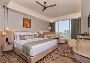 a bedroom with a large bed and a large window at The Forum Hotel and Convention in Ahmedabad