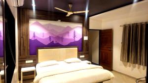 a bedroom with a bed with a mountain mural on the wall at Vardhan Lodge in Ajra