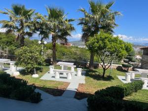 a park with white benches and palm trees at Vila 3 palmat in Ksamil