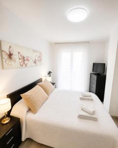 a bedroom with a large white bed with two towels on it at Apartamento TIERRA in Viveiro