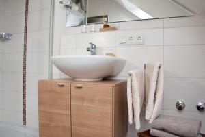 a bathroom with a white sink on a wooden cabinet at Pension Sperlhof in Erding +31 photos
