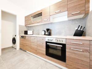 a kitchen with wooden cabinets and a stove at Tolstov Apartments - Monteurwohnungen - 2 Schlafzimmer - Küche - Balkon - Waschmaschine in Heiligenhaus