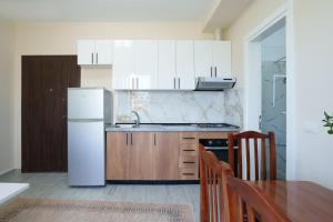 a kitchen with a white refrigerator and a table and chairs at Sea Vibe Apartment in Polisi i Vogël