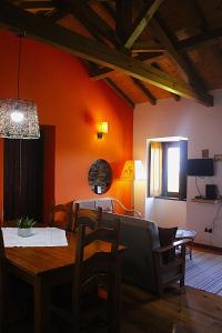 a dining room with a table and chairs and a room with orange walls at Casa da Comareira in Góis